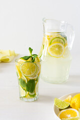 Summer refreshing drink of lemon, lime and mint, jug with lemonade and glasses and citrus slices