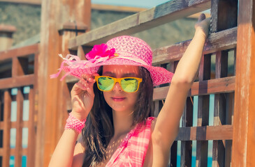 Summertime portrait of young girl in a swimsuit standing by the wooden fence