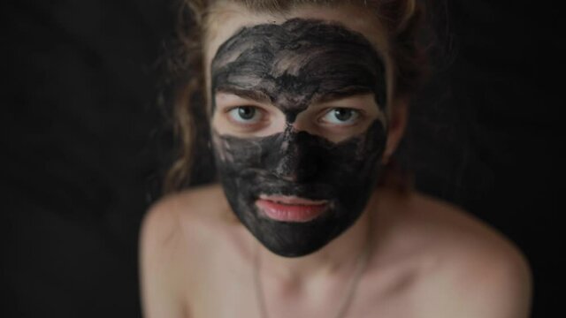 Crazy girl with coal mask frighten on camera 