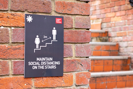 COVID 19 safety information sign for shoppers mounted on brick wall leading to stairs