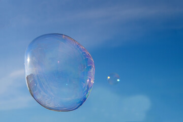 Soap bubble against a blue sky with buildings reflected in it