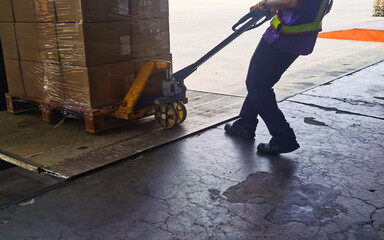 Worker loading and unloading shipment carton boxes and goods on wooden pallet by forklift  from container truck to warehouse cargo storage in logistics and transportation industrial 
