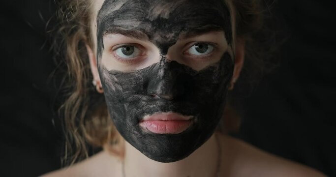 Girl with coal mask on skin looking at the camera 
