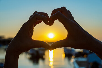 hands making heart shape  at the sunset