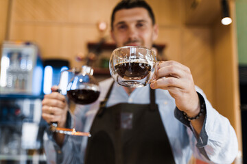 Double glass cup with coffee in cafe. Barista gives a cup of coffee to you. Alternative coffee brewing using Syphon device.