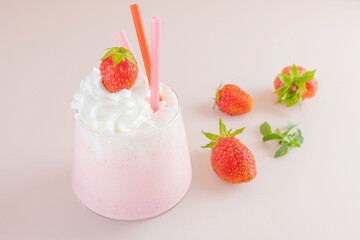 Strawberry milkshake on a light background in a transparent glass. Around - strawberries. The concept of delicious fresh drinks, healthy food for breakfast and snack.