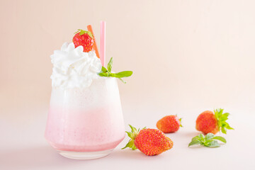 Strawberry milkshake on a light background in a transparent glass. Around - strawberries. The concept of delicious fresh drinks, healthy food for breakfast and snack.