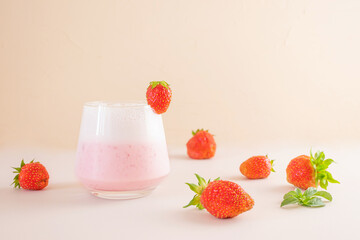 Strawberry milkshake on a light background in a transparent glass. Around - strawberries. The concept of delicious fresh drinks, healthy food for breakfast and snack.