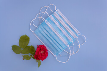 medical protective mask and rose on a blue background