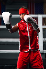 Kids sport concept. Girl sportsman muay thai boxer fighting in gloves in boxing gym.