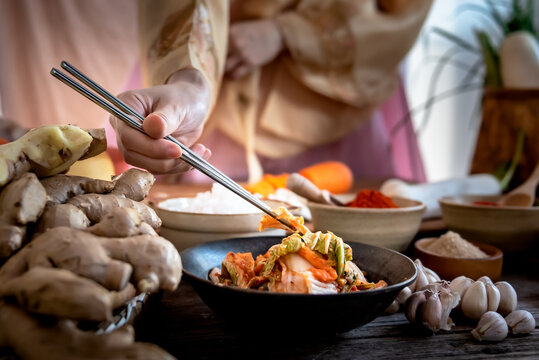 Blurred soft images of woman Wearing a traditional hanbok, using chopsticks to eat Kimchi which made from the fermentation of vegetables Is the preservation of Korean food