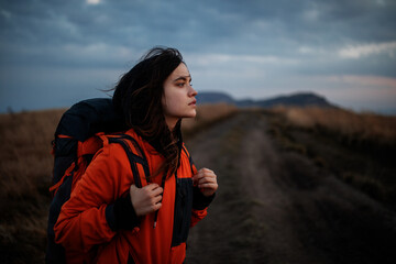 Portrait of a tourist girl with a backpack. Young beautiful woman traveling in the mountains - 363322895