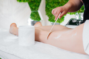 A young pretty girl is enjoying a professional massage using honey at the Spa. Body care. Beauty salon