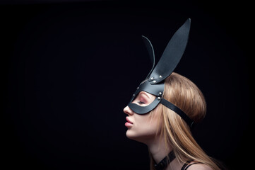 A girl in a black carnival mask. Posing on a black background in the Studio.