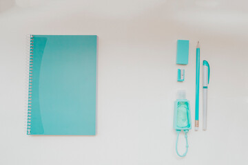 Close up picture of office stationery on light background. Notebook located on left side and pen, pencil, sanitizer on right side, so in the missile empty space for text. Back to school concept.