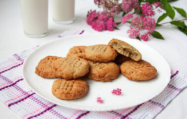 homemade peanut cookies with milk and pink flowers on the white background
