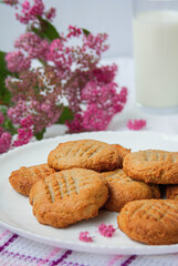 homemade peanut cookies with milk and pink flowers on the white background