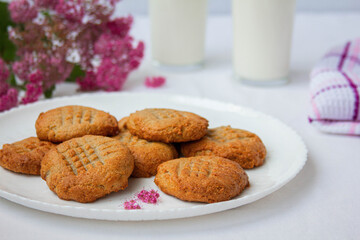 homemade peanut cookies with milk and pink flowers on the white background