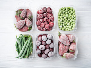Top view of frozen berries and vegetables in plastic boxes on a light background