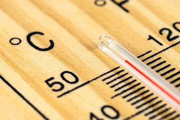 A macro shot of a classic wooden thermometer showing a temperature over 50 degrees Celsius, 122...