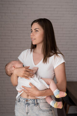 Closeup portrait of a young mom. A woman holds a newborn baby in her arms. Parental love.