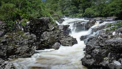 Fototapeta na wymiar Long exposure shot of the waterfalls in Glen Orchy near Bridge of Orchy in the Argyll region of the highlands of Scotland during summer whilst the river is flowing fast from rainfall
