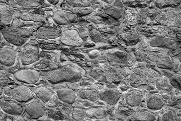 Monochrome stone wall texture background. Fragment of a massive wall of an ancient building.