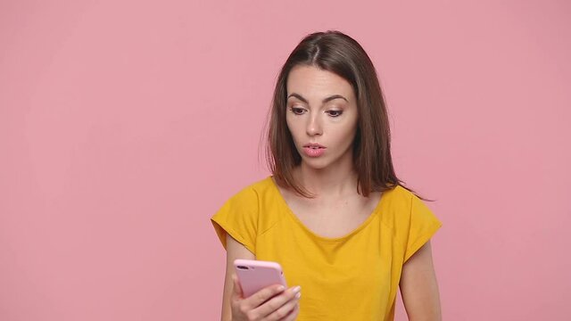 Boring girl 20s in yellow t-shirt get video call using mobile cellphone doing selfie videoconference conducting pleasant conversation isolated on pastel pink background studio People lifestyle concept