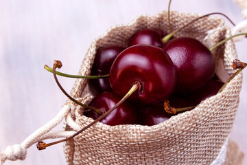 Sweet cherry in fabric bag on light background close up
