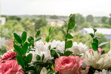 Bouquet of flowers in a box given to any wife for the anniversary. Bunch of flowers with roses, daisies and greenery on a window background. Close up.