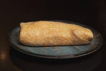 Large stuffed pancake with meat and mushrooms on a beautiful vintage plate against a dark background. Dishes of traditional Russian cuisine.