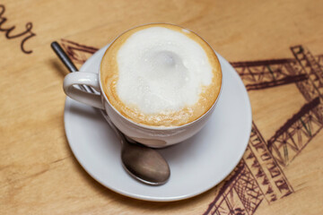 A white cup of cappuccino with lush milk froth on a beautiful table in a cafe. Delicious drinks for breakfast.