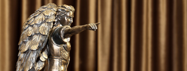 A bronze statuette of the Archangel Michael points a finger forward.