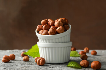 Bowls with hazelnuts on gray table. Vitamin food