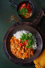 Chicken tikka masala spicy curry meat food in marbre plate with rice and spices on dark gray background. Indian food recipe.