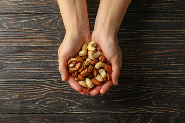 Woman holds different nuts on wooden background. Healthy eating