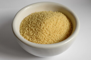 Dry couscous in white ceramic bowl isolated on white. 