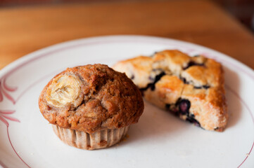homemade rustic banana muffin wit blueberry scone on white plate 