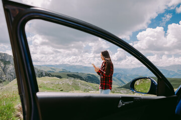 beautiful woman traveller using smartphone and travel by car in mountains. Pretty woman on road trip using smartphone and relax in mountains with landscape view. 