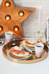 Toasts with cream cheese, smoked salmon, avocado and poached egg. Cup of coffee.