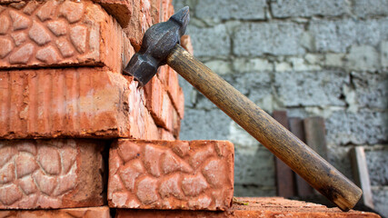 Bricks and a hammer in the foreground. Object of construction. Red dust from building materials. Copy space