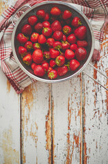 Freshly harvested strawberries. Metal colander filled with juicy fresh ripe strawberries on an table