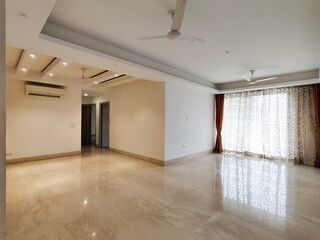 Wide angle shot of a huge apartment with false ceiling lights, curtains on windows polished marble floor