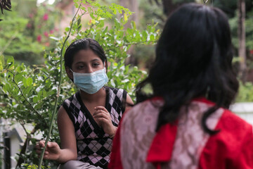 masked girl playing outdoor while keeping social distance during the global pandemic.