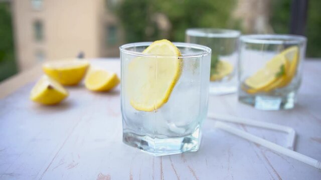 pouring soda water in glass with lemon. refreshing summer cocktail concept with tonic or transparent alcohol