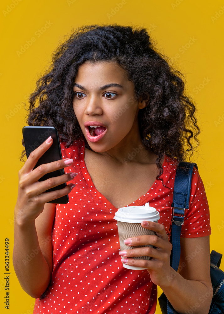 Wall mural Vertical shot of amazed girl student reading message with amazing news that she won in online lottery at her smartphone