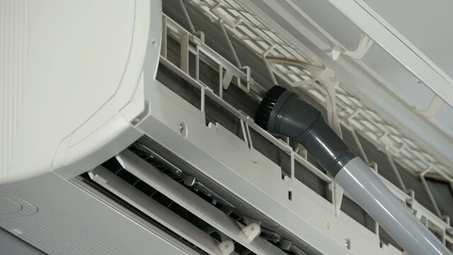 technician service using vacuum cleaner to cleaning the air conditioner