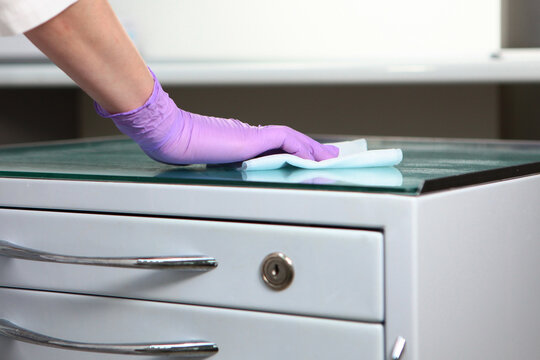 Disinfection of furniture in the dental office. Preparing the office for receiving patients. Close-up of a gloved hand. Copy of the space. Unrecognizable photo.