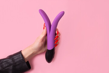 Dildo in hand on a pink background, sex toy