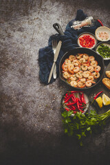 Grilled shrimps in cast iron grilling pan with fresh lemon, parsley, chili, garlic white wine sauce